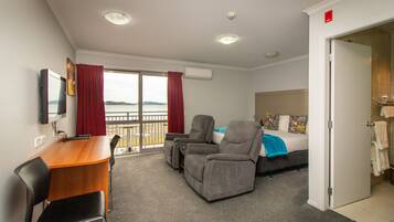 A hotel room with a balcony, a desk with a chair, a sofa, and a bed.