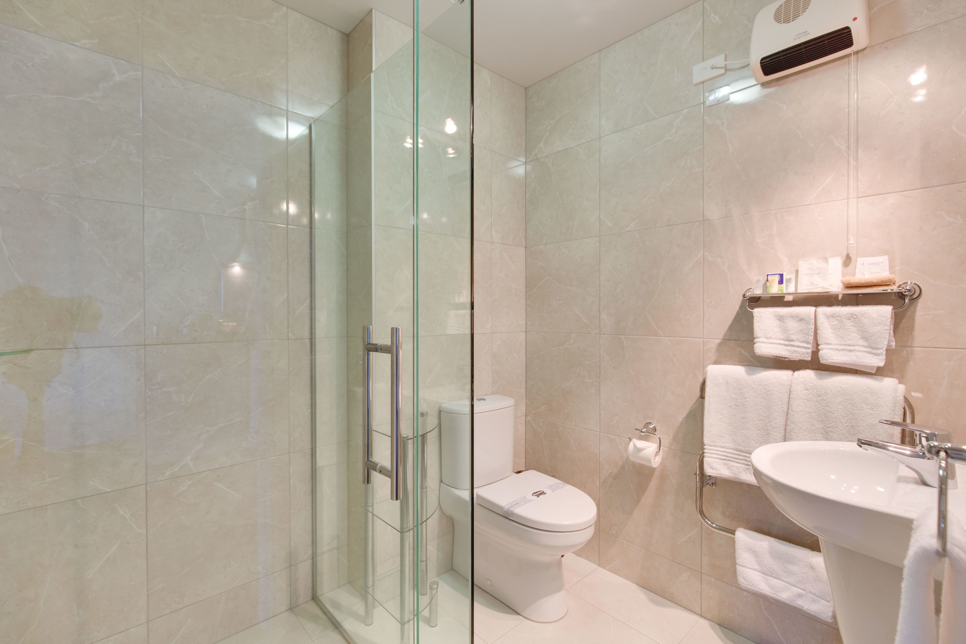 Ein modernes Badezimmer mit einer Duschkabine aus Glas, einer Toilette und einem Waschbecken mit Handtuchhalter.