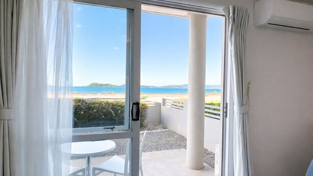 Ein Balkon mit Blick auf das Meer, einem weißen Tisch und einem blauen Stuhl.