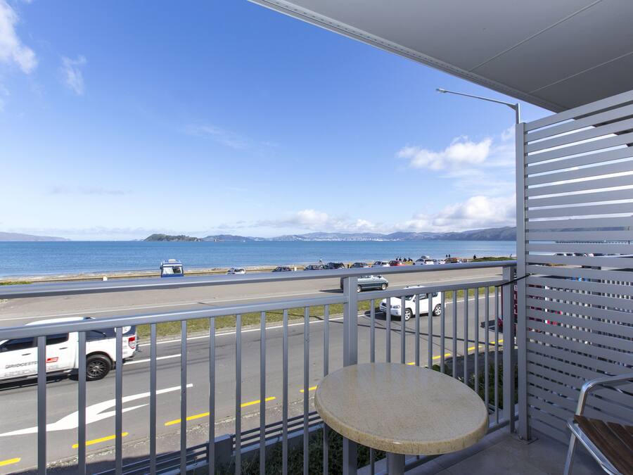 A balcony with a view of a road and the sea.