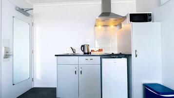 A compact kitchen with a microwave, stove, and refrigerator.