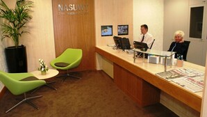 Un área de recepción con un mostrador de madera, dos sillas verdes, una planta en maceta y un letrero en la pared que dice "NASUWT The Teachers' Union".
