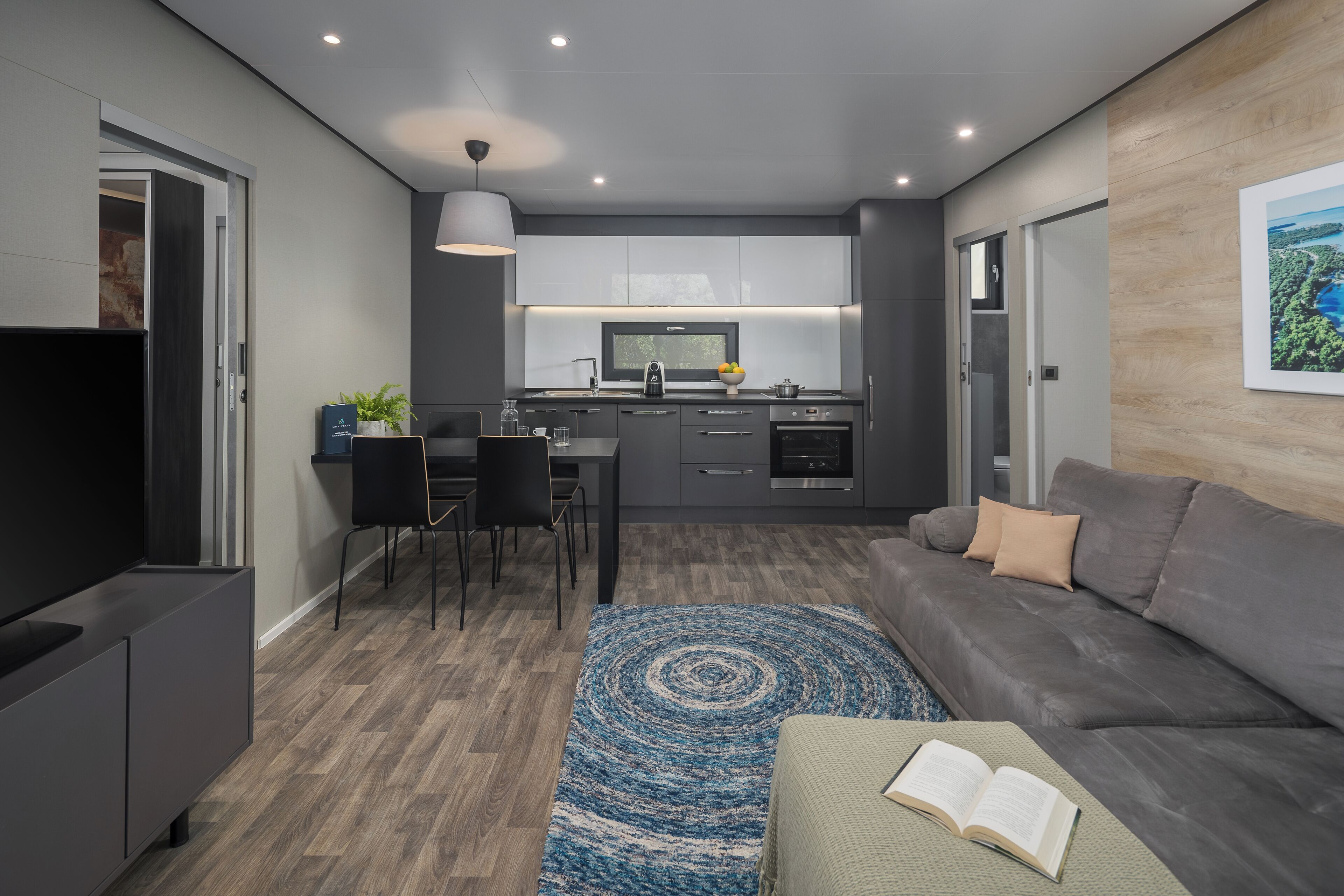 Una sala de estar moderna con un sofá gris, una mesa de centro con un libro y un mueble para televisión.