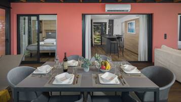 Zona pranzo con tavolo apparecchiato per quattro, cucina sullo sfondo e una porta scorrevole in vetro che dà su un balcone.