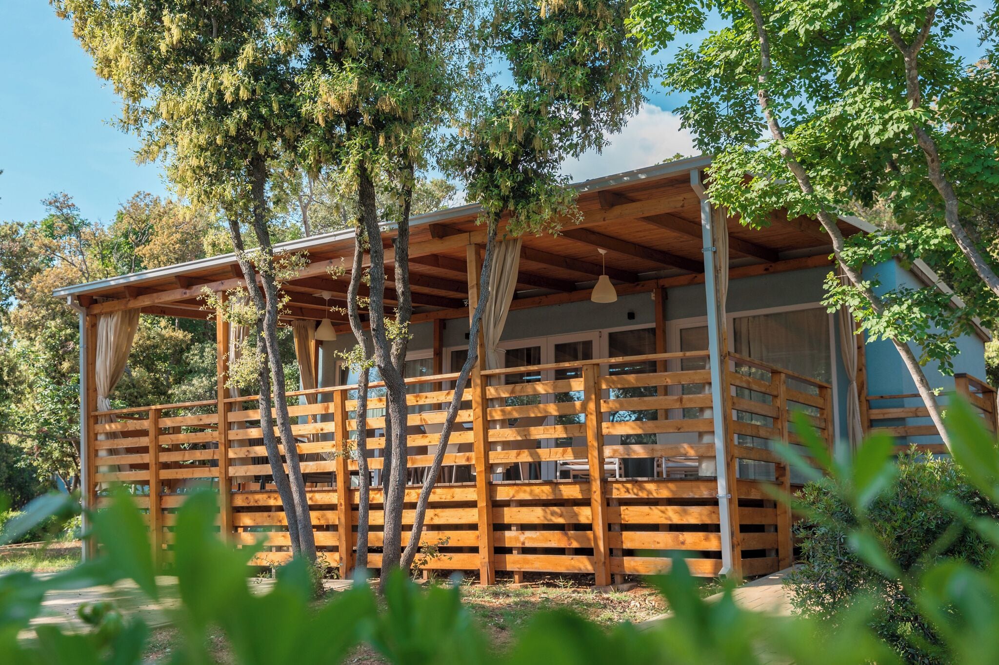 A wooden cabin with a balcony, surrounded by trees.
