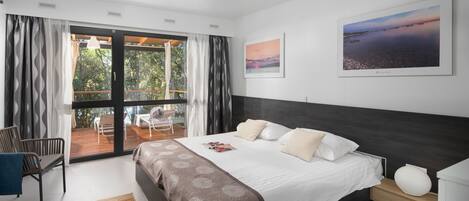 Un dormitorio moderno con una cama grande, vistas al exterior a través de una puerta corredera y un cuadro enmarcado en la pared.