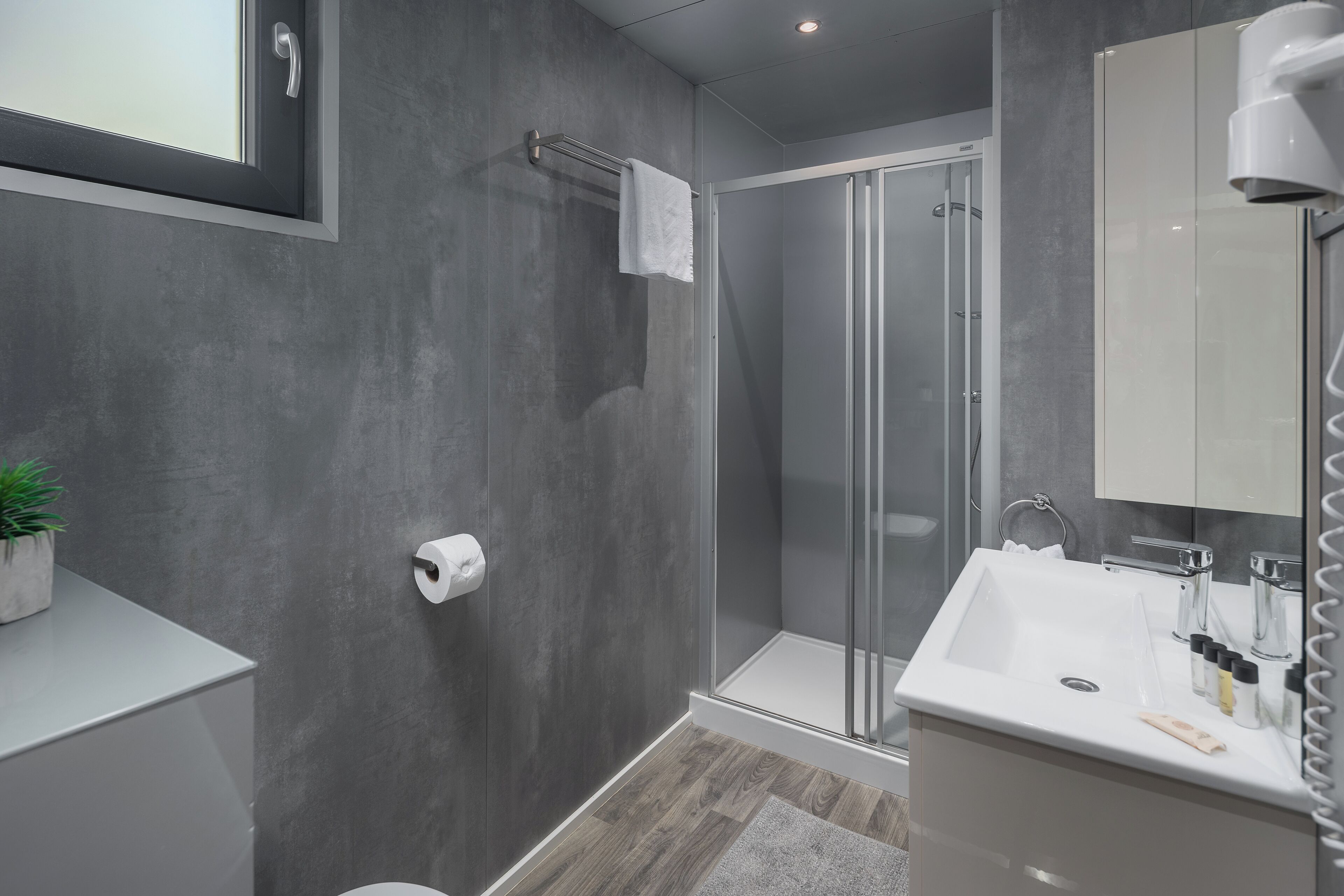 A modern bathroom with a shower, a sink, and a toilet.