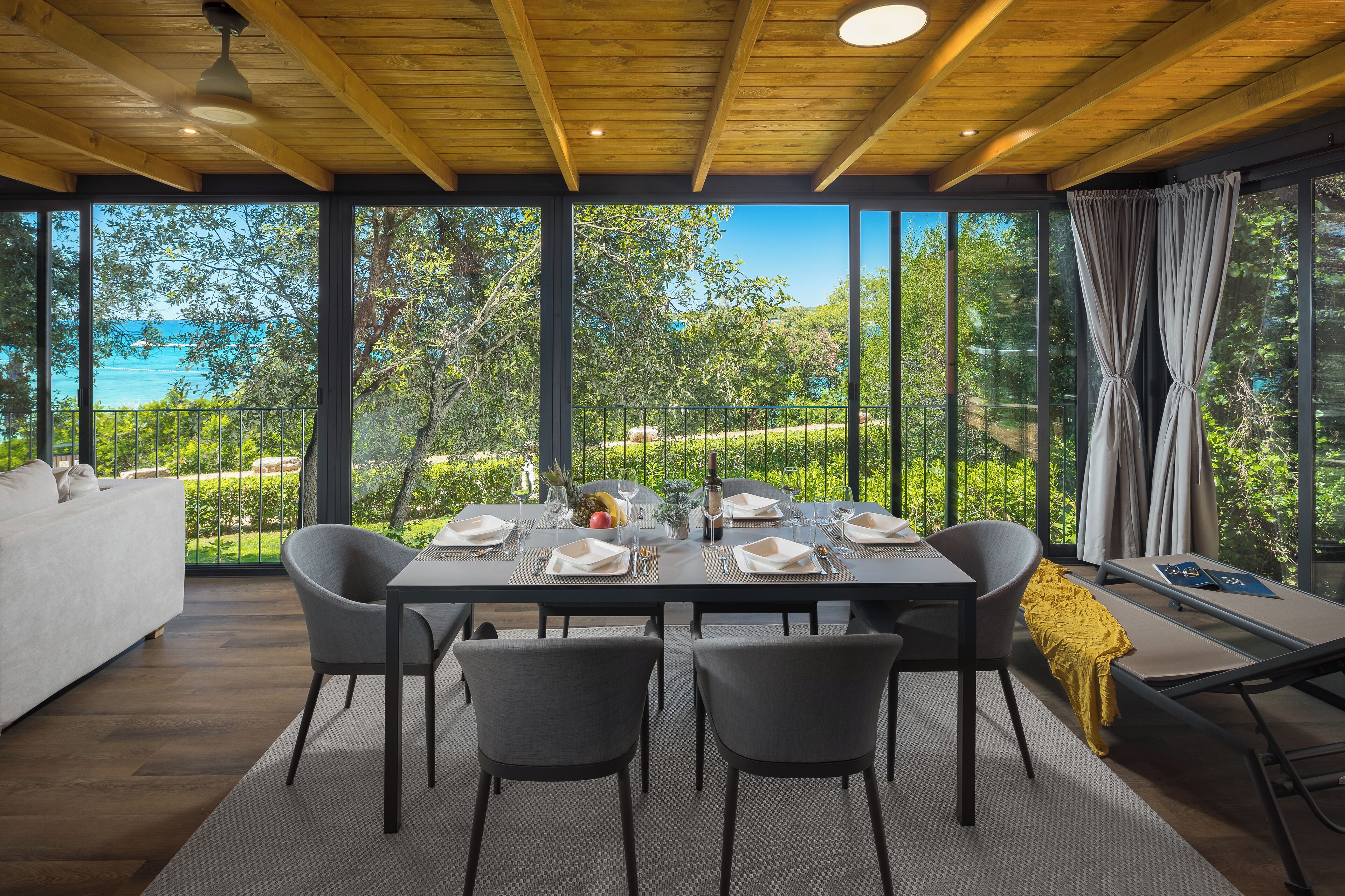 A dining area with a table set for four, large windows, and a view of the outdoors.