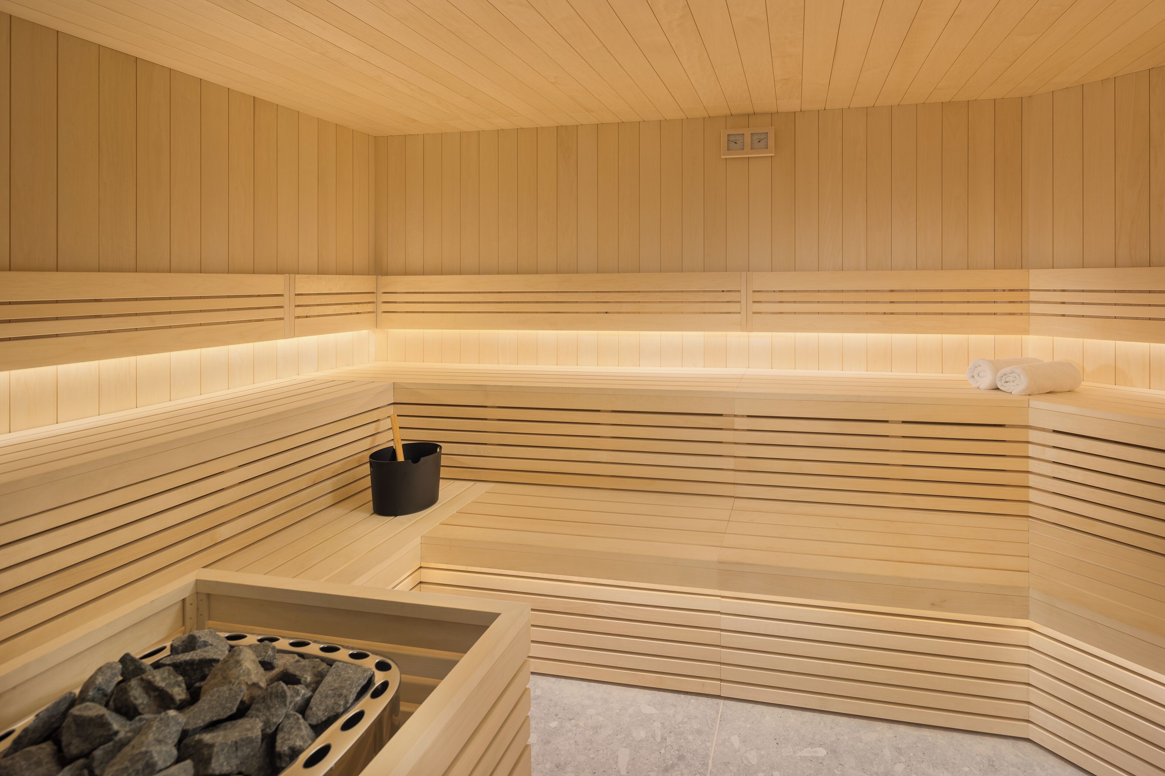 A sauna with wooden paneling, a bench, and a seating area with towels.