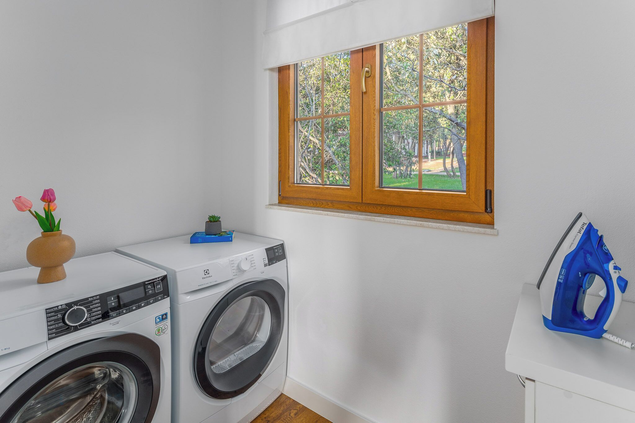 Un espace buanderie équipé d’un lave-linge, d’un sèche-linge et d’une planche à repasser.