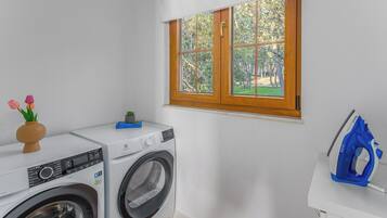 A laundry area with a washing machine, dryer, and an ironing board.