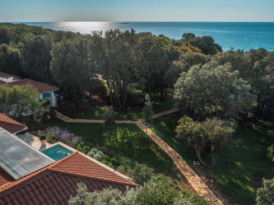 A residential property with a swimming pool, solar panels, and a view of the sea.