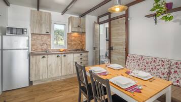 Une cuisine avec des meubles en bois, un pare-feu en pierre et un coin repas avec une table en bois mise pour quatre personnes.