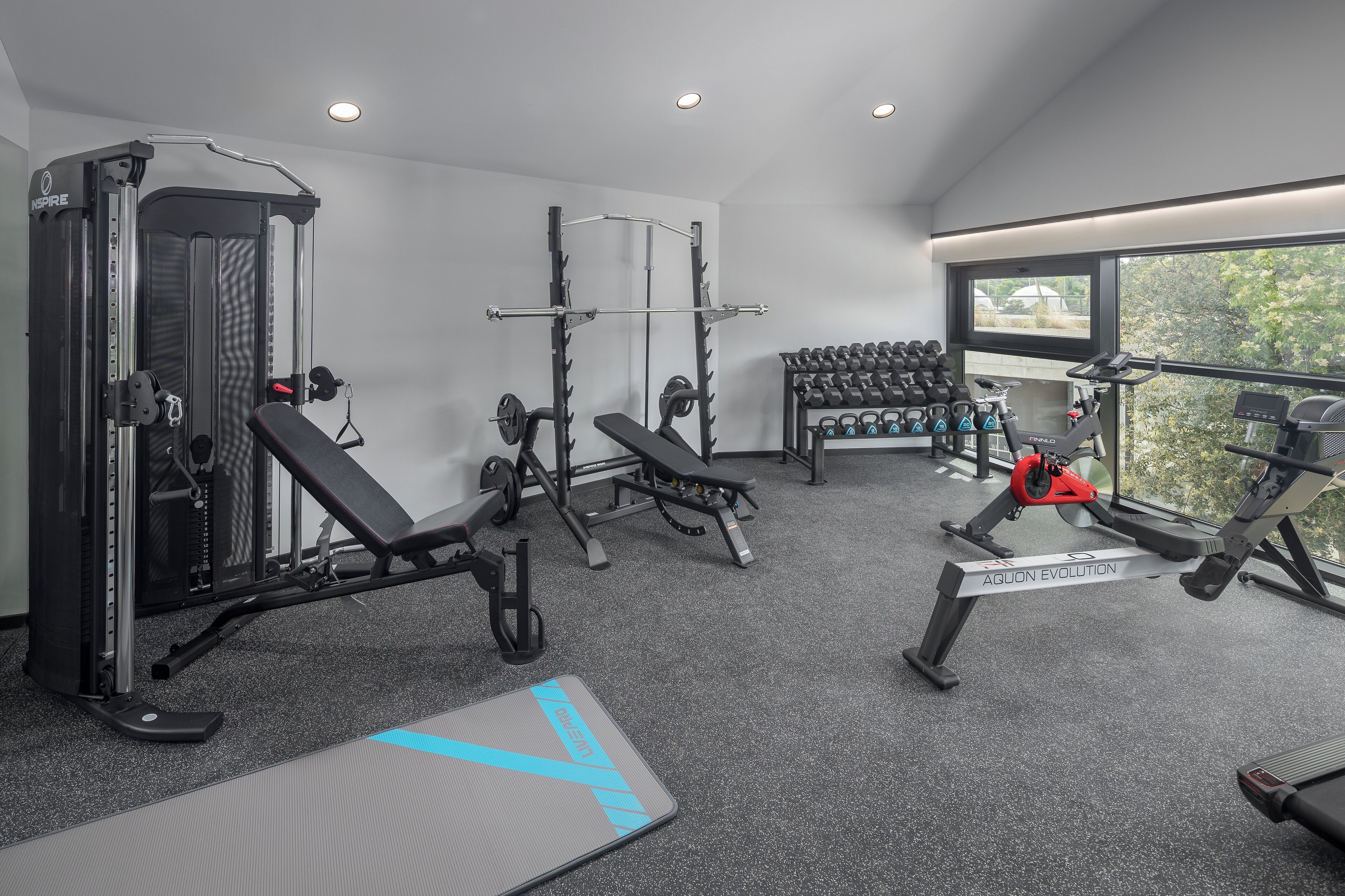 Una palestra moderna con diverse attrezzature, tra cui una panca per squat, una panca per distensione e macchinari cardio.