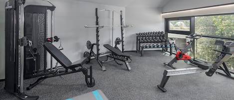 Un gimnasio moderno con diversos equipos, incluyendo una estructura para sentadillas, una prensa de banca y máquinas de cardio.
