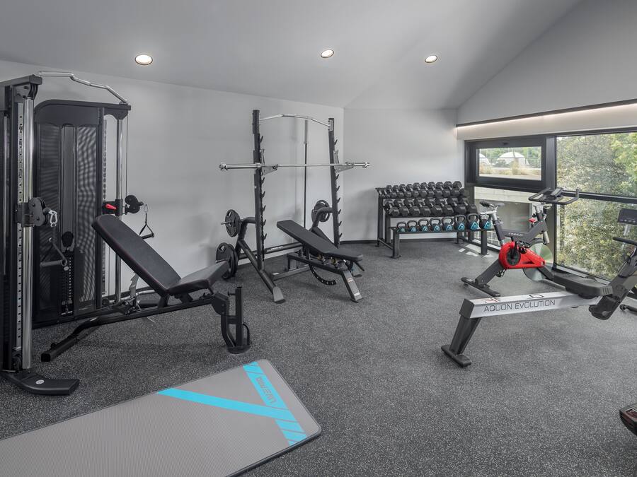 Ein modernes Fitnessstudio mit verschiedenen Geräten, darunter ein Squat-Rack, eine Hantelbank und Cardiogeräte.
