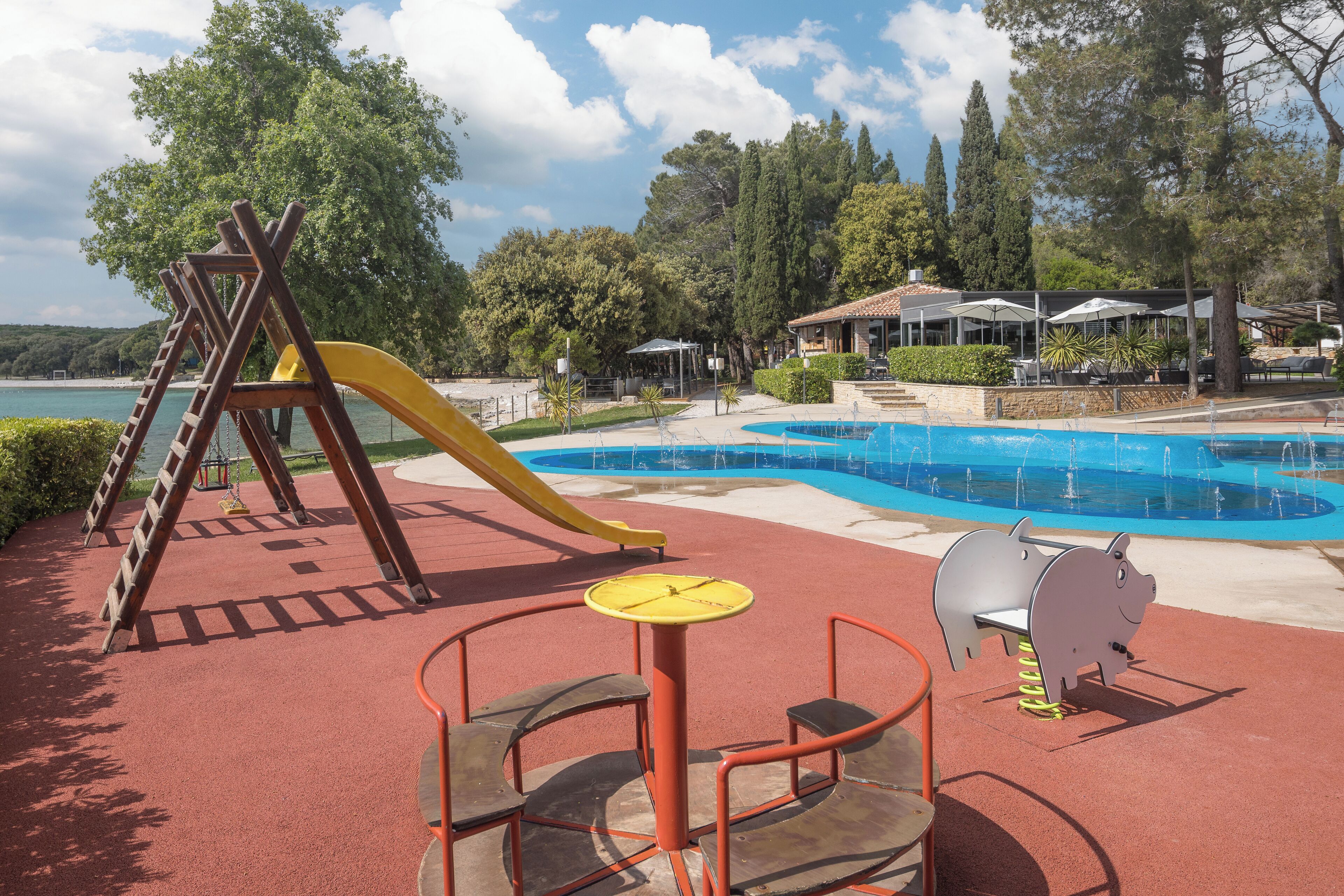 A playground with a slide, swings, and a small table with chairs.