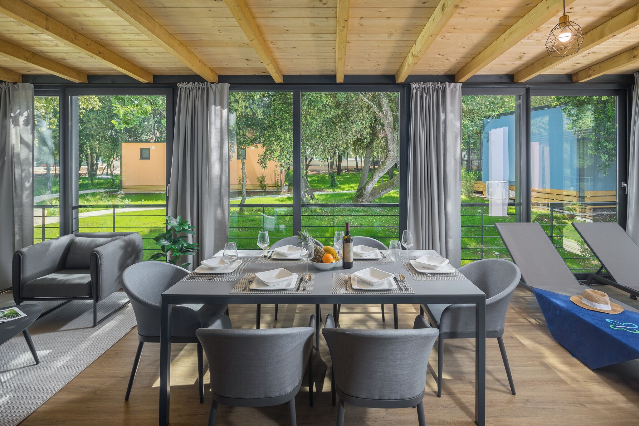 A dining area with a table set for four, large windows, and a view of a garden.