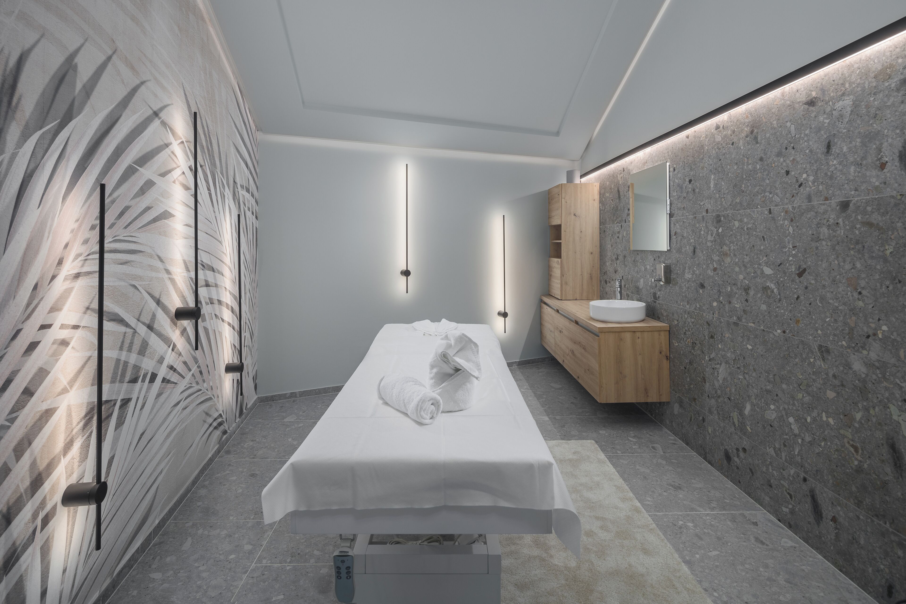 Een moderne badkamer met een marmeren wand, een houten wastafelmeubel, een witte wasbak en een handdoek op de vloer.