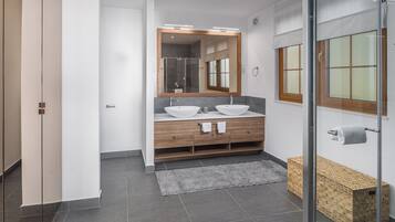 Un baño moderno con dos lavamanos, un espejo grande y una cabina de ducha de vidrio.