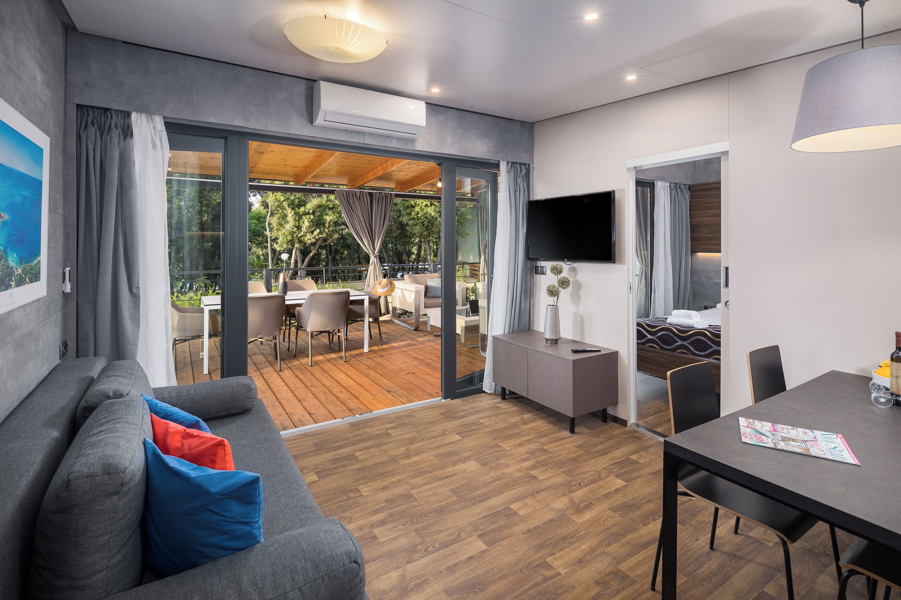 Een moderne woonkamer met een bank, eettafel en uitzicht op een terras.