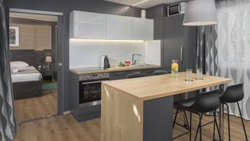 A modern kitchen with a central island, black bar stools, and a large pendant light.