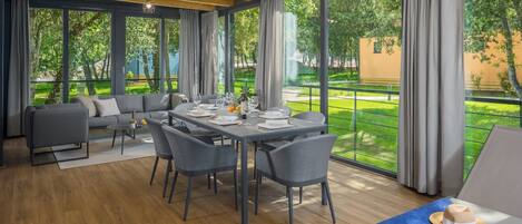 A dining area with a table set for four, a sofa, and a lounge area with a table and a hat.