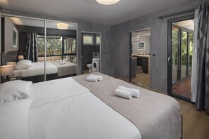 A modern hotel room with a large bed, a washing machine, and a sliding glass door leading to a balcony. - Camping Homes Mon Perin (Bale)