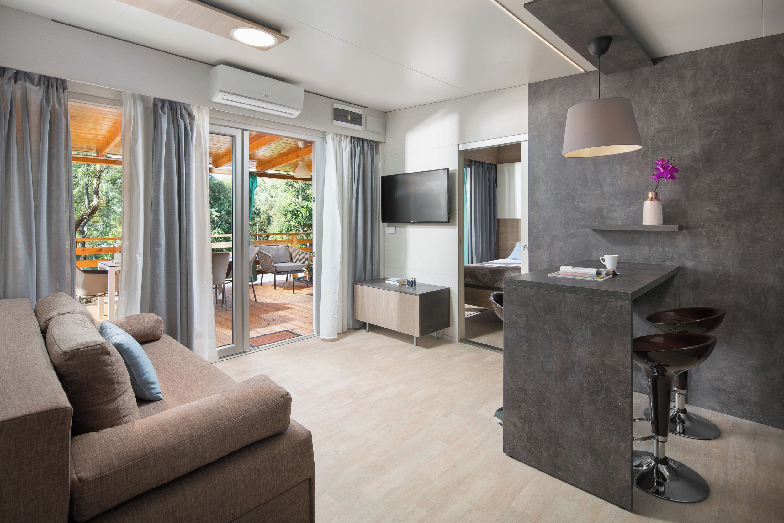 A modern living room with a sofa, a TV, and a dining area with a table and chairs.