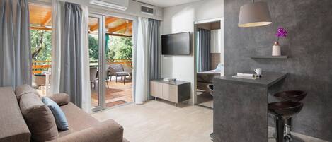 A modern living room with a sofa, a TV, and a dining area with a table and chairs.
