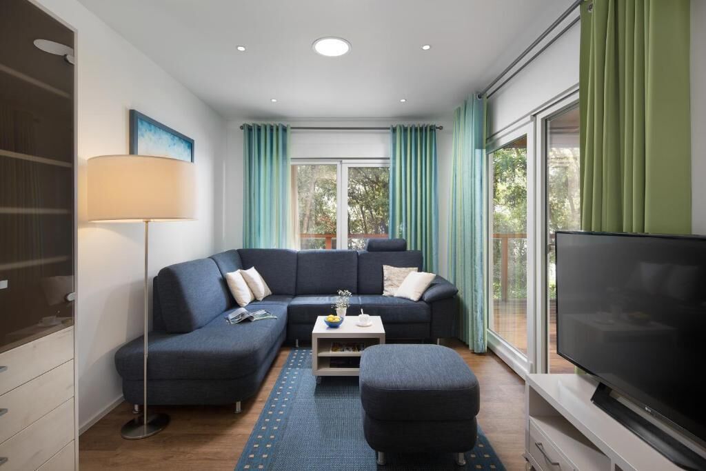 A modern living room with a dark blue sectional sofa, a flat-screen TV, and a coffee table.