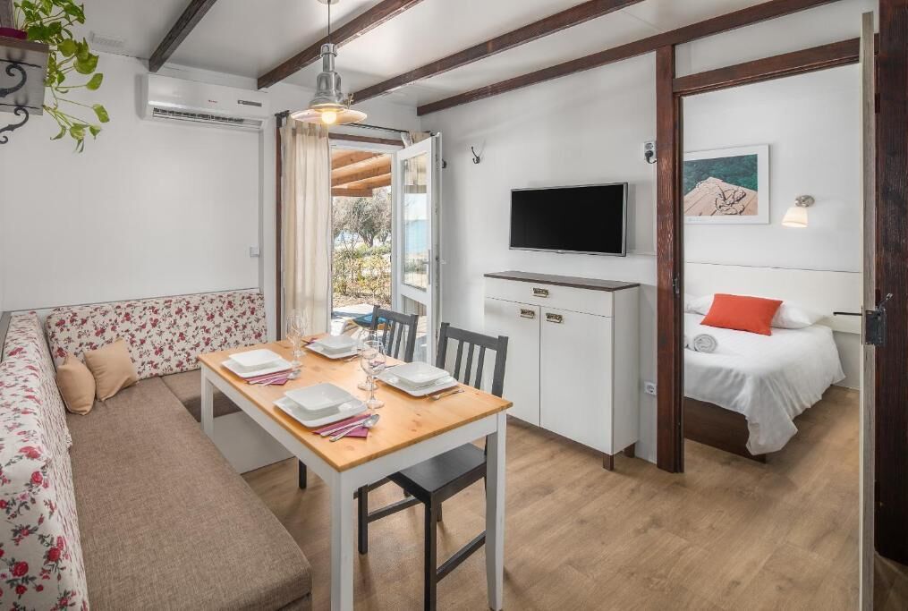 Une pièce de taille modeste comprenant une table à manger, un canapé, un lit, un téléviseur et une petite kitchenette.