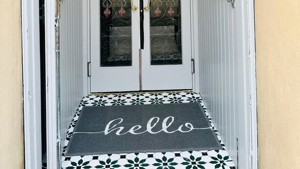 A hotel entrance with a 'hello' mat, a 'no smoking' sign, and a security camera. - Eliza House (Edinburgh)