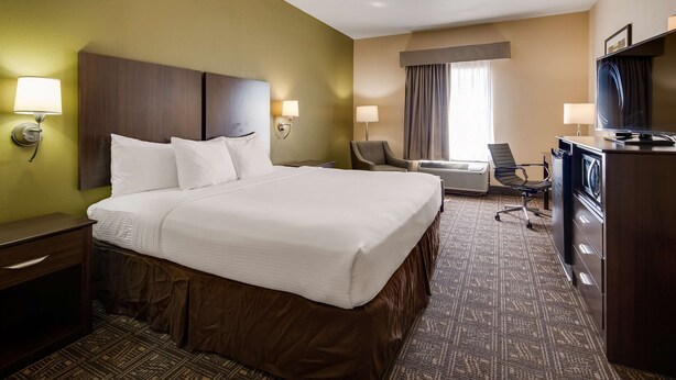 Een hotelkamer met een groot bed, twee bedlampen, een bureau, een stoel, een televisie en een airconditioning.