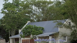 A house with a grey roof, surrounded by trees and a fence.