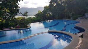 Una piscina al aire libre, sombrillas, sillones reclinables de piscina