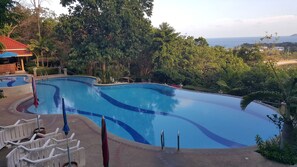 Una piscina al aire libre, sombrillas, sillones reclinables de piscina