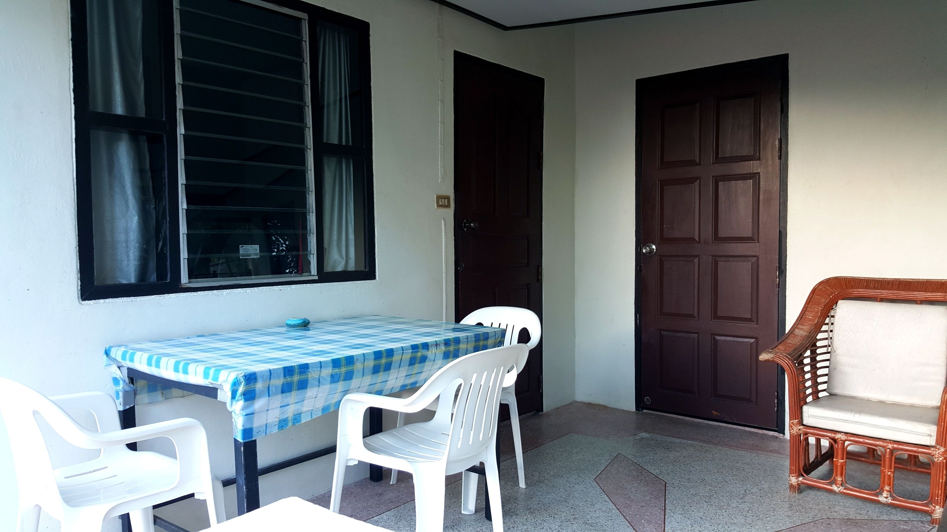 A small room with a table and chairs, a door, and a window with curtains.