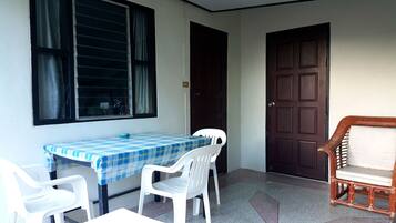 A small room with a table and chairs, a door, and a window with curtains.