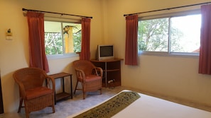 A room with two wicker chairs, a small table, a television on a stand, and a window with curtains. - Baan Suan Sook Resort (Koh Samui)