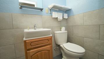 A bathroom with a sink, wooden cabinet, toilet, and towel rack.