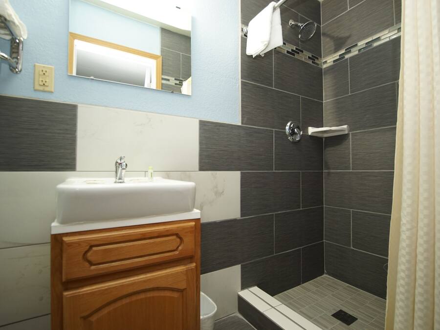 A bathroom with a sink, mirror, and shower.