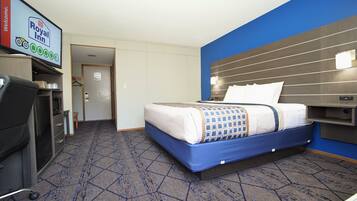 A hotel room with a bed, a desk, a chair, and a television displaying the Royal Inn logo.