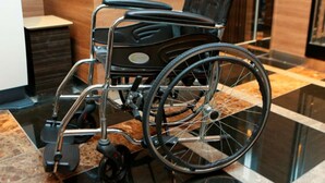 A wheelchair in a modern lobby with a marble floor and wooden paneling. - APA Hotel Sagamihara Hashimoto Ekimae (Sagamihara)
