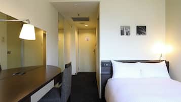A hotel room with a bed, a desk, a chair, a lamp, and a water dispenser.