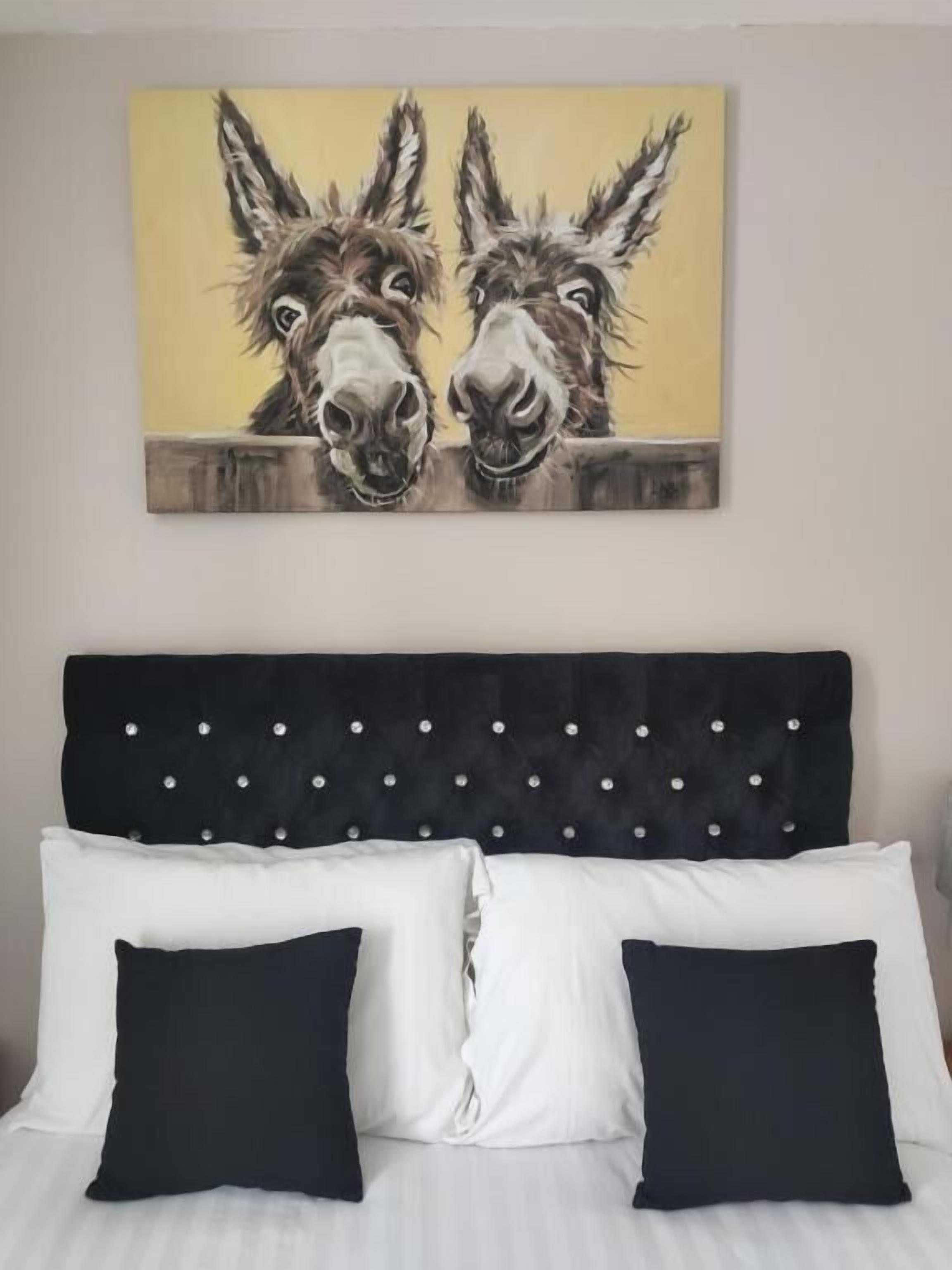 A bed with a tufted headboard and two pillows, one white and one black.