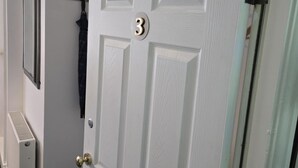 A white door with the number 3, a coat rack, and a radiator. - Q Accommodation (Blackpool)