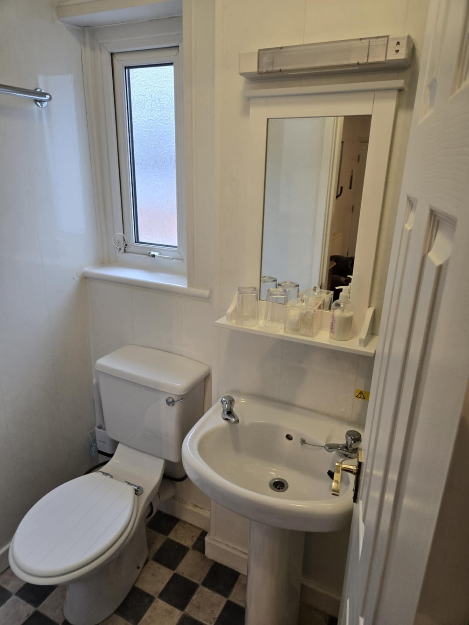A small, clean bathroom with a toilet, sink, and window.