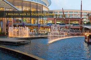 A shopping center with a water fountain and a building with multiple levels and balconies. - The Allano Phuket Hotel (Patong)