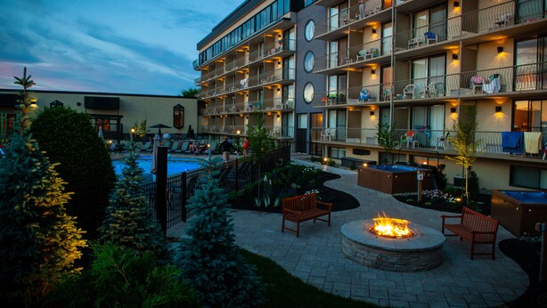 Un hotel de varios pisos con piscina al aire libre, fogata y zonas de estar.